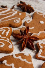 Fresh baked decorated gingerbread with spices on old wooden background, christmas time