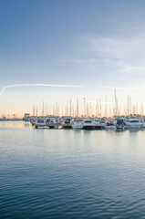 Fototapeta na wymiar Large yacht harbor in purple sunset light, luxury summer cruise, sailboats in sunrise, leisure time, active life, vacation and holidays concept Yachts and their reflection in the city's port