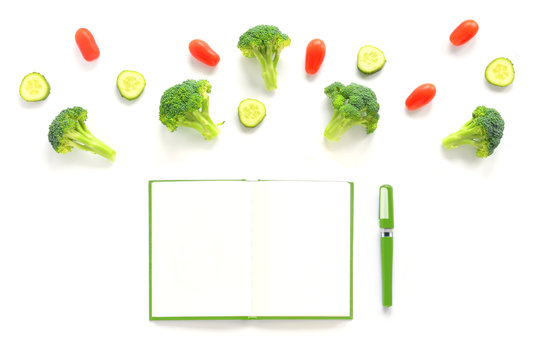 Broccoli, tomatoes and cucumbers composition with green notebook