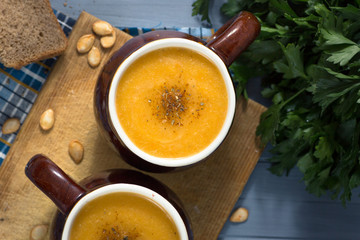pumpkin cream soup in mugs on  gray blue background