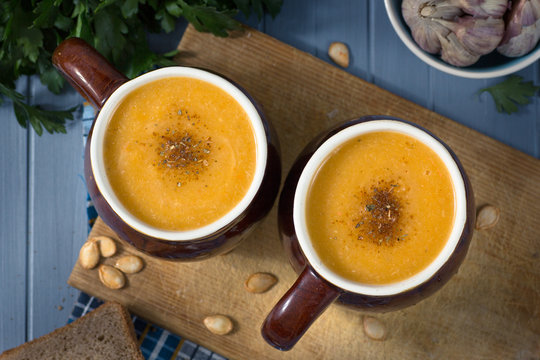 pumpkin cream soup in mugs on  gray blue background