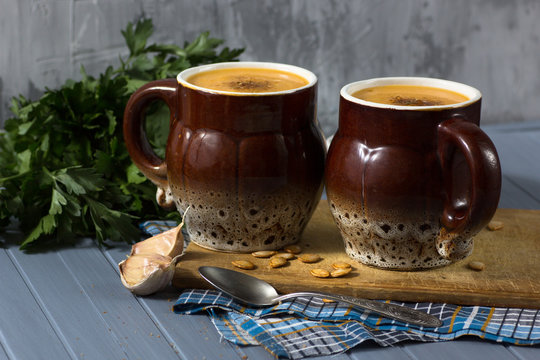 pumpkin cream soup in mugs on  gray blue background