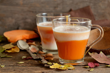 Home latte with milk, almonds and pumpkin on a wooden background