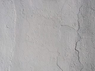 The old plastered background on a building wall with cracks and chips
