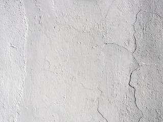 The old plastered background on a building wall with cracks and chips