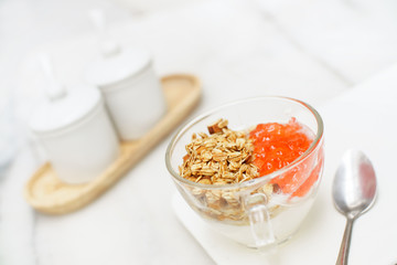 Granola yogurt with strawberry jam cup on marble table