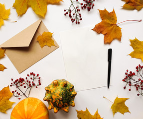 Stylish composition of letter, pumpkins, autumn leaves, berries. Top view on white background. Autumn flat lay