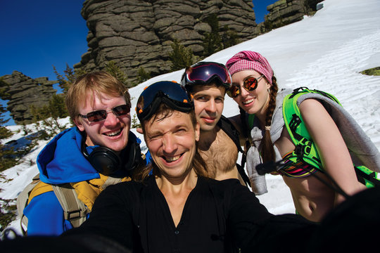Group of happy friends snowboarding doing selfie