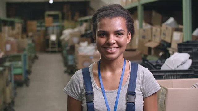 Portrait of Latin-American female worker standing in warehouse posing for camera and laughing