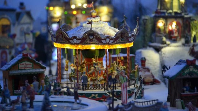 Close-up of Christmas carousel in a small courtyard. Miniature fabulous courtyard with a children's carousel with horses, toy passers. Flashing lights Christmas decorations. Dreamland.Kiev.01/24/2016