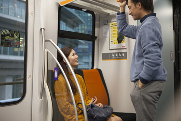 Train in a man is standing, women are sitting in the priority seat