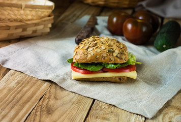Healthy sandwich with cheese, tomatoes, lettuce on a linen towel, in rustic style