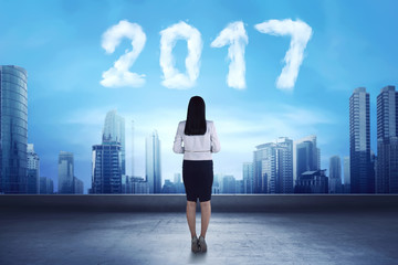 Fototapeta na wymiar Asian business woman looking cloud shaped number 2017