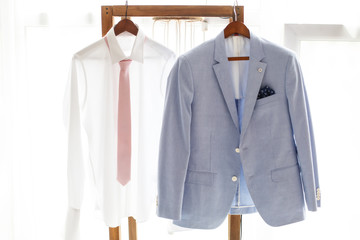 White shirt and gray suit of groom hanging on hanger