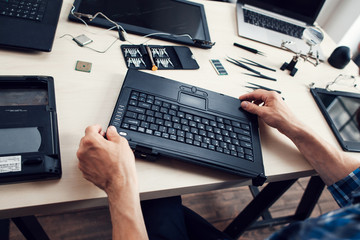 Keyboard of disassembled laptop, repairman pov. Engineer workplace with necessary tools. Electronic...