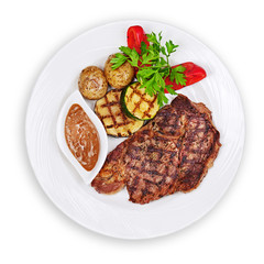 Grilled steak, baked potatoes and vegetables on white plate isolated on white background.