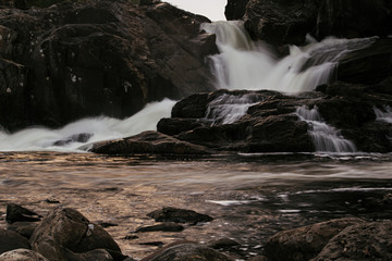 Waterfall with reflection glare of  setting sun. Arctic summer, the tundra, Norway.