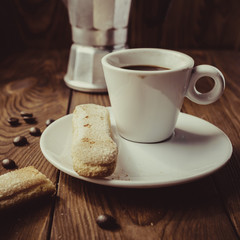 Cup of hot espresso, moka pot and cookies on the wooden table