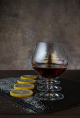 Four glasses of cognac on the background of lemon slices with sugar