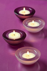 burning candles on purple background