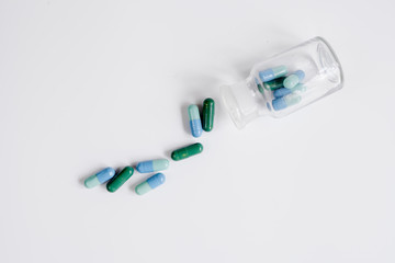 colored pills in glass bottle on white background