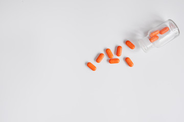 orange pills in glass bottle on white background