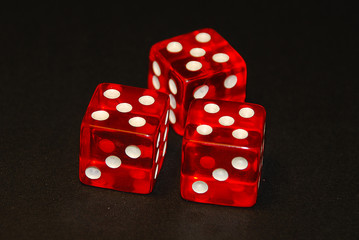 three dice on a black desk, result fifteen (15), doublets of fiv