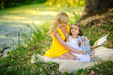 mother reads the book in the daughter on a grass