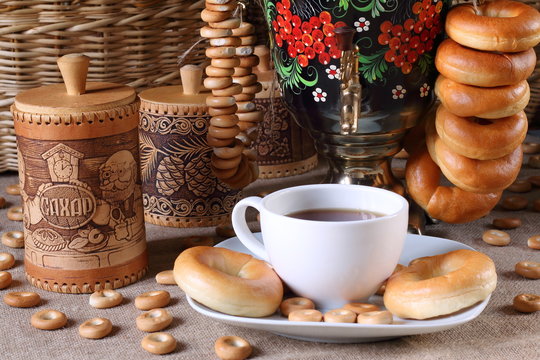 Самовар, кружка с чаем, калачи и баранки.