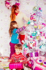 Mother and kids decorate a Christmas tree together