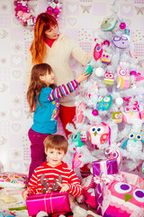 Mother with the kids are decorating a Christmas tree