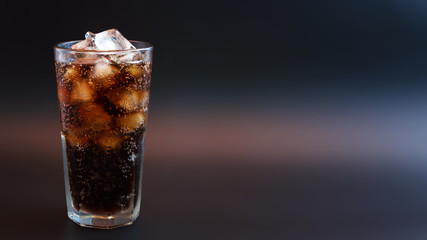 Cola with ice in glass on black background 