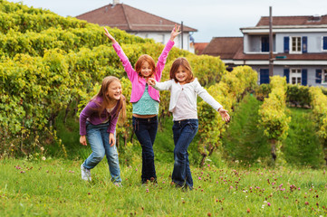 Fototapeta premium 3 little girls having fun outdoors, wearing denim jeans and colorful t-shirts