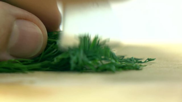 Cutting fresh green dill on wooden board. Cooking 4K macro video