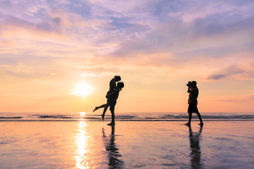 Photographer taking photo of romantic couple kissing on the beach