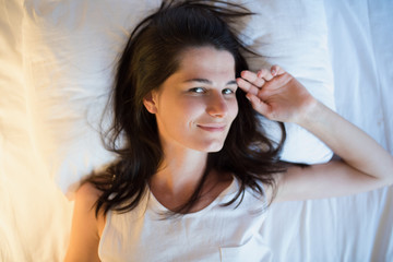 Naklejka premium Beautiful natural woman on the white bed. View from above
