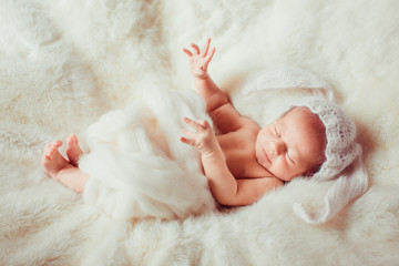 newborn lying on blanket in a white hat rabbit