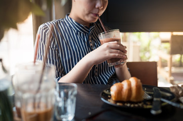 Woman eating croissant in cafe