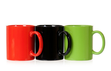 Three color coffee cups - red, green and black, isolated on white background. Set of ceramic motley mugs for tea with clipping path.