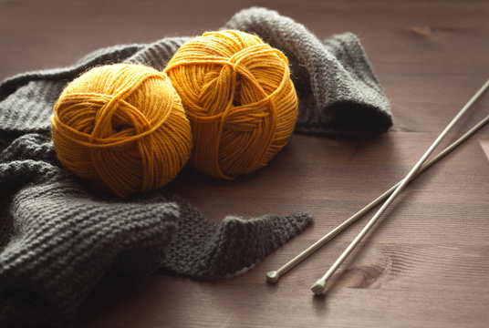 yellow yarn with gray scarf on a brown wood backgrownd