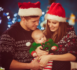 Warm picture of glad parents dressed in winter pyjamas and holdi
