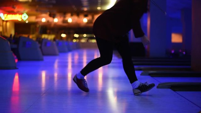 Girl throws ball in bowling