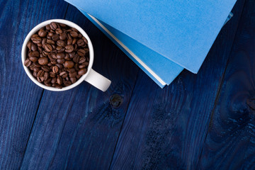 mug full of coffee beans and two blue books