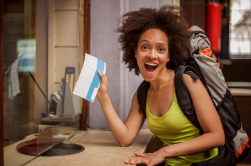 Very happy and euphoric backpacker female tourist shows her purchased ticket for her long-awaited trip