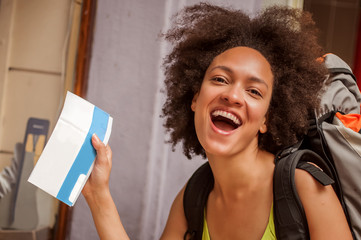 Very happy and euphoric backpacker female tourist shows her purchased ticket for her long-awaited...