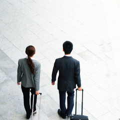 back of young woman and businessman with luggages from top