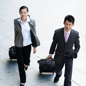 young woman and businessman with luggages from top