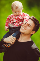 Kid closes father's eye while sitting on his shoulder