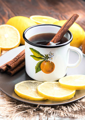 Hot black tea with cinnamon stick Lemon slices on plate Rustic