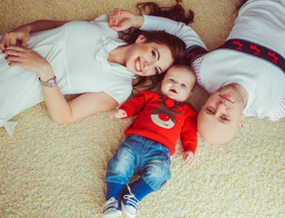 The happinest mother,father  and  son lie on the bed